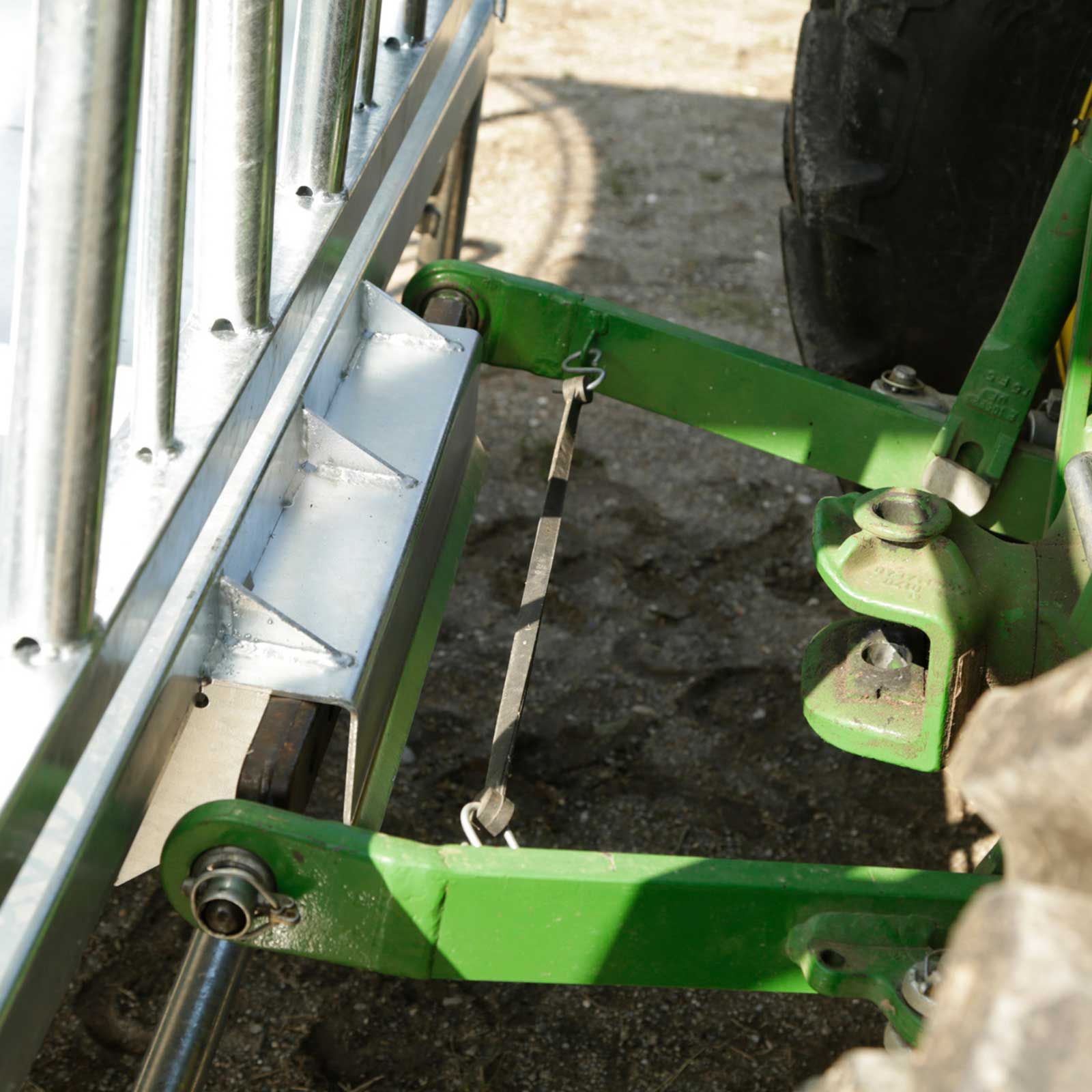 Attelage trois points vert d'un tracteur près d'une clôture grillagée