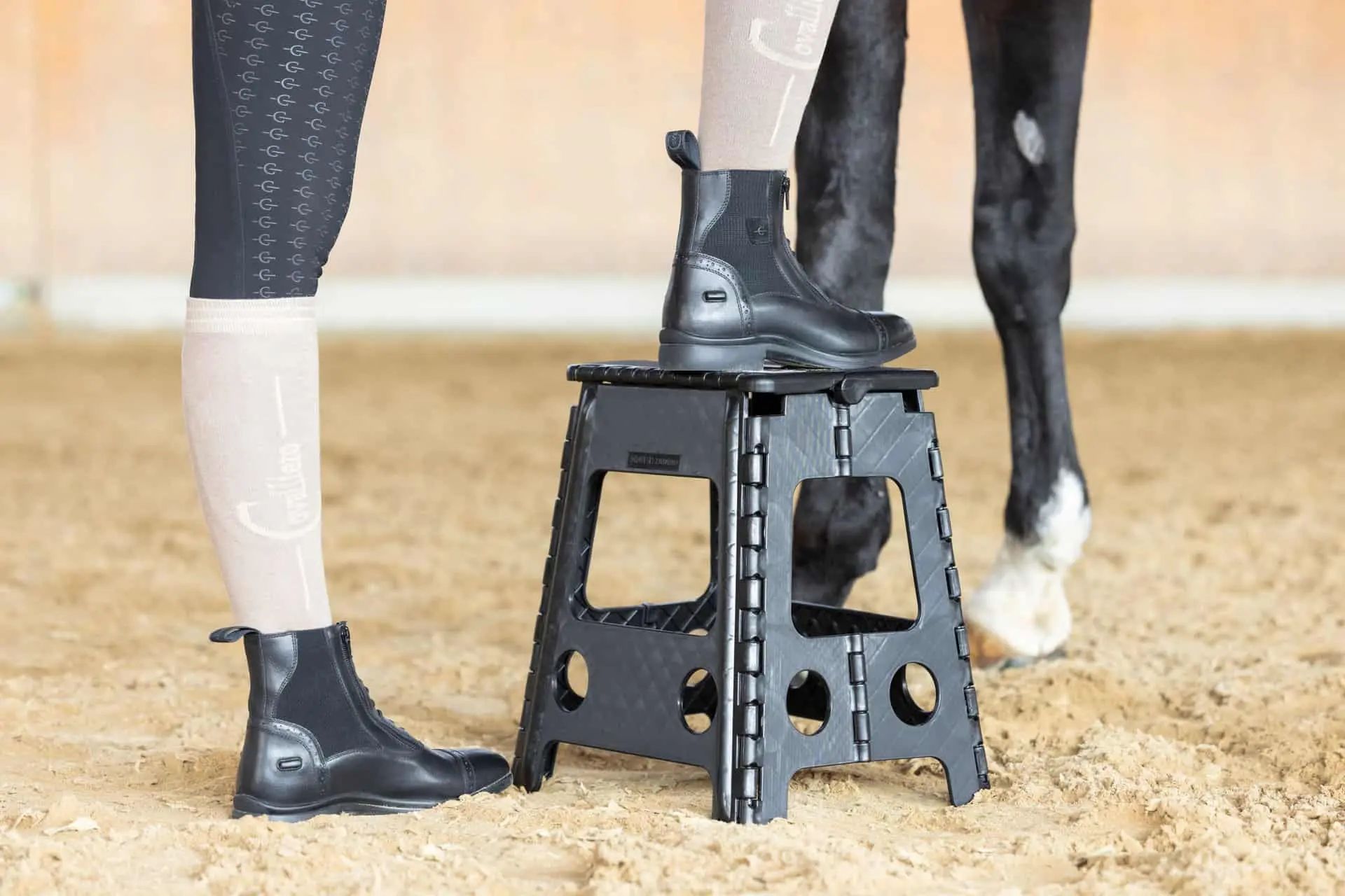 Personne en bottes d'équitation sur un marchepied pliant noir près d'un cheval