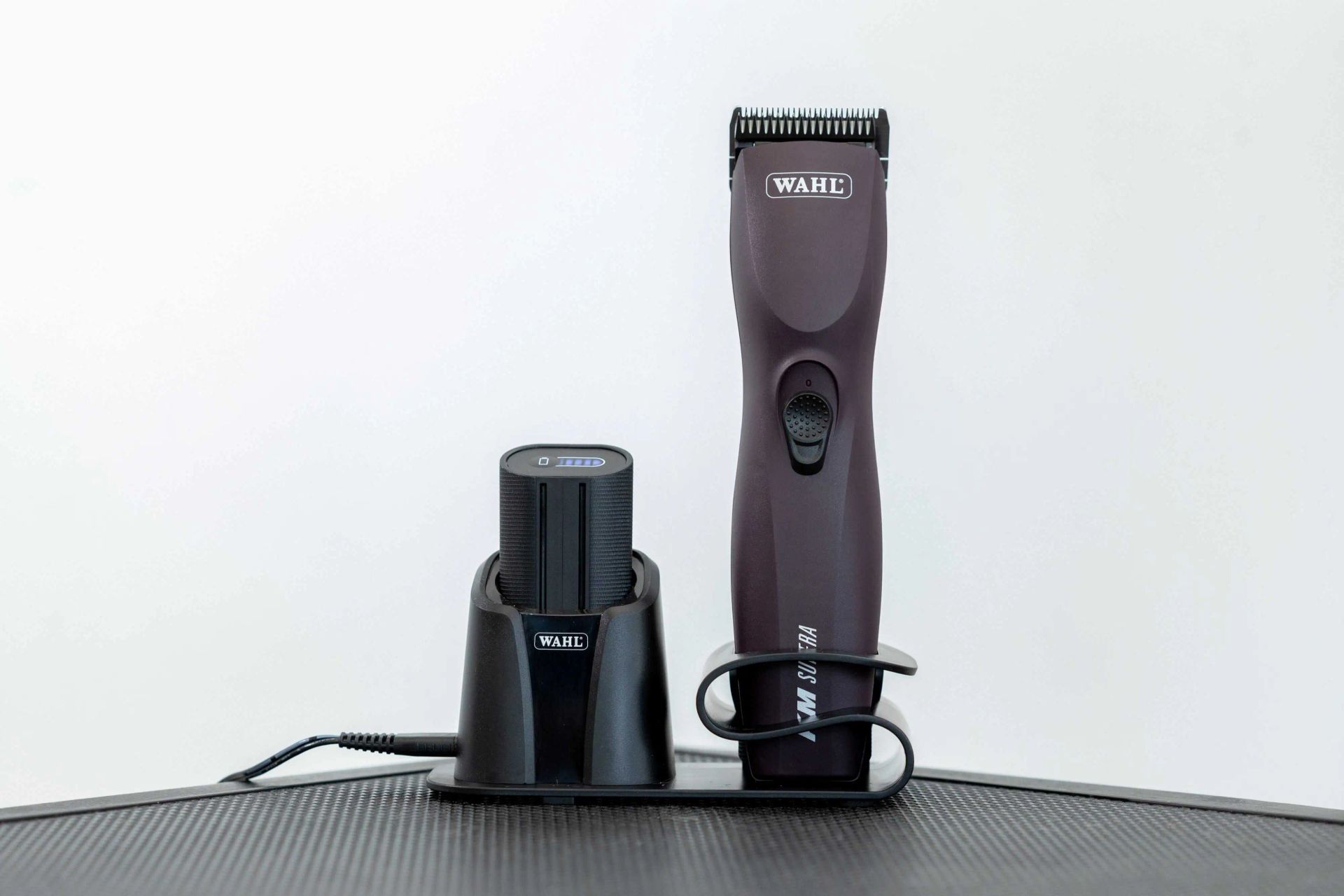 Wahl Schermaschine neben Ladestation mit Akku auf schwarzer Unterlage