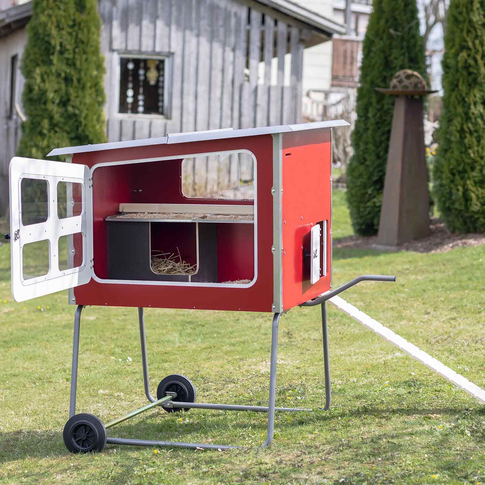 rotes fahrbares Kleintierhaus mit Fenster und Stroh im Garten