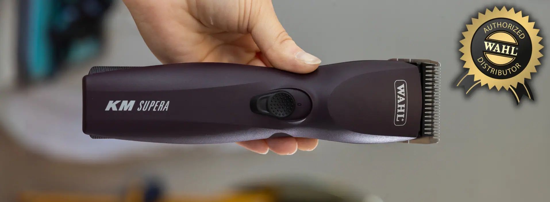 Schwarze Schermaschine mit der Aufschrift KM Supra wird in der Hand gehalten
