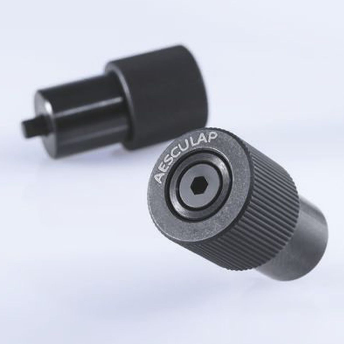 Zwei schwarze zylindrische Metallaufsätze mit Aufdruck Aesculap