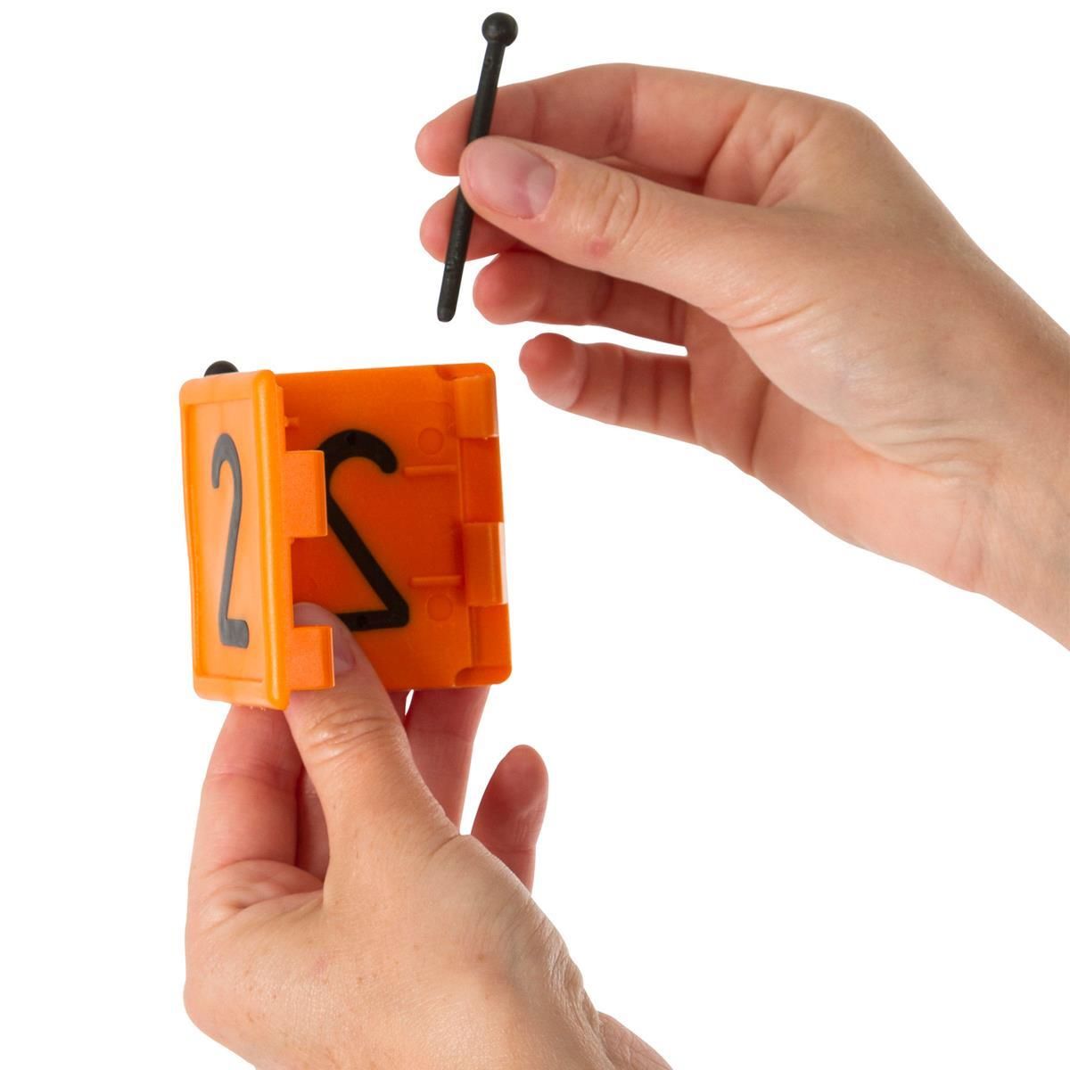 Orangefarbener Zahlenwürfel mit Ziffer 2, Hand hält Nagel zur Befestigung