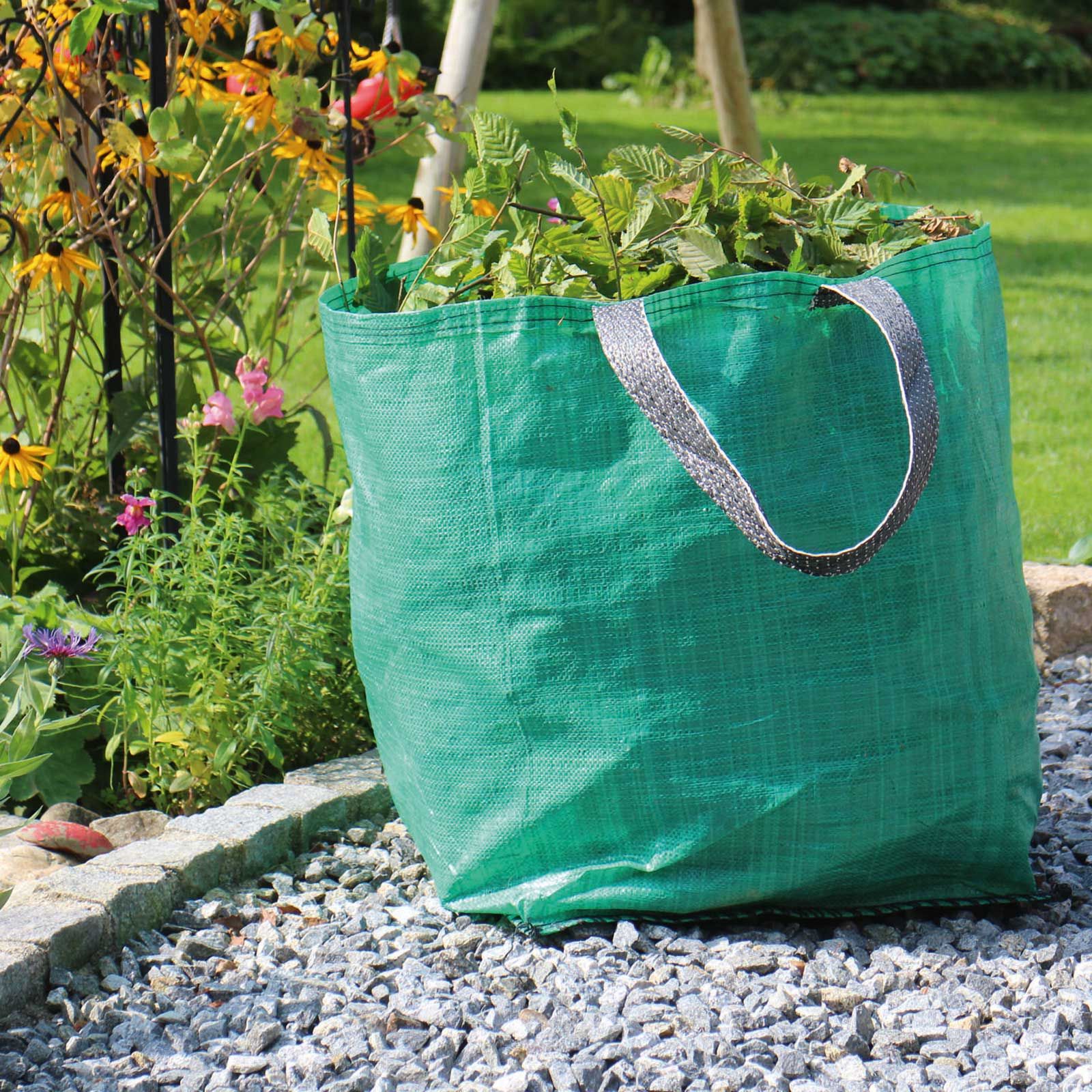 Sac vert à déchets verts avec poignées, rempli de tontes, posé sur des graviers